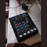Černý mixážní pult značky ALTO PROFESSIONAL s nápisem TRUEMIX 500 na spodní hraně. Zařízení obsahuje několik vstupů, regulační knoflíky a posuvníky v…