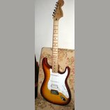 Elektrická kytara s tylem z jasného dřeva a korpusem v přechodovém žluto-hnědém odstínu (sunburst). Na hlavě je nápis Squier STRATOCASTER. Nástroj má…