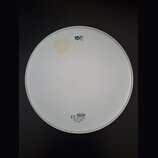 Bílá kruhová bubenová koží s bílým plastovým okrajem. V horní části je černý nápis 15" a v dolní části logo s korunkou a texty REMO, UT DRUM HEAD, MA…