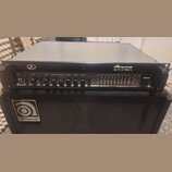 Černý basový zesilovač s nápisem Ampeg SVT-3 PRO umístěný na černé basové reproducing box s logem Ampeg. Přední panel zesilovače obsahuje ovládací kn…