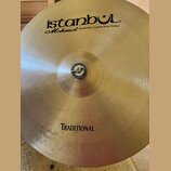 Zlatý kovový činel s viditelným opracováním povrchu. V horní části je černý nápis istanbul® a pod ním kurzívou Mehmet Handmade Cymbals from Turkey. V…