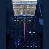 Fotografie zachycuje černý DJ kontrolér Traktor Z1, který je připojen k notebooku s otevřeným softwarem TRAKTOR PRO 4. Na zařízení jsou vidět dva mod…