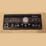 Černý monitor kontroler s nápisem BIG KNOB STUDIO COMMAND SYSTEM. Zařízení obsahuje centrální ovladač VOLUME, sekce INPUT SOURCE SELECT s tlačítky DA…