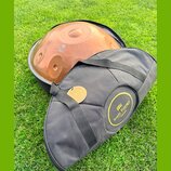 Na fotografii je kovový nástroj typu handpan v měděné barvě, umístěný v černé přepravce. Na povrchu nástroje je nápis „Handpan Design Sela“. Před nás…