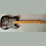 Elektrická kytara typu Telecaster s černým korpusem, který je zdoben šedivým ornamentem paisley. Kytara má šedý plech s podobným vzorem, javorový hma…