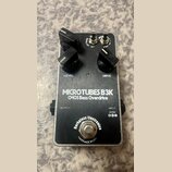 Stompbox s kovovým stříbrným povrchem a černým spodním panelem. Na horní části jsou tři černé ovládací knoflíky s popisky LEVEL a DRIVE, dva přepínač…