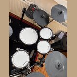 Elektronická bicí souprava značky Alesis. Na module je nápis Alesis a Crimson 1, na bubnech jsou viditelná loga Alesis. Souprava obsahuje čtyři bílé…