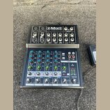 Černý kompaktní mixážní pult s nápisem Mix8 8-CHANNEL COMPACT MIXER. Horní část obsahuje vstupy Gain a AUX, spodní část je vybavena modrými a zeleným…