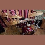 Celá bicí souprava v tmavě červené barvě s kovovým hardwarem. Na tomu a snare drumu je viditelné logo „PD“. Souprava obsahuje basový buben, dva tom-t…