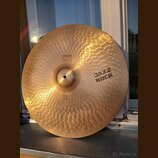 Kovový činel s výrazným kování povrchu v podobě drobných jamů. Na povrchu jsou černé nápisy „paiste 2002“, „JAZZ ROCK“ a v dolní části „HEAVY RIDE“.…