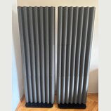Dva šedé akustické panely s vlnovitým povrchem. Panely jsou umístěny na černých základnách. Na povrchu nejsou vidět žádné značky ani nápisy.