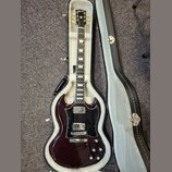 Tmavě vínová elektrická kytara s černým pickguardem v tvrdém kufru s bílou výplní. Na hlavě hmatníku je zlatý nápis Gibson. Kytara má dva humbuckery,…