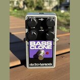 Stříbrný efekt pedál v kovovém šasi s fialovým panelem. Na panelu je bílý nápis BASS CLONE a v dolní části černý pruh s bílým logem electro-harmonix.…