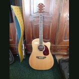 Akustická kytara s cutawayem v přirozené dřevěné barvě a červeným puntovaným pickguardem. Na hlavě hmatníku je viditelné logo Epiphone. Hmatník obsah…
