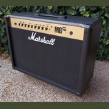 Kytarový kombozesilovač značky Marshall v černé barvě s gold panelem. Na přední mřížce je bílé logo Marshall a na ovládacím panelu nápis MG 100FX. Ho…