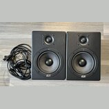 Dva černé studiové monitory s logem ESI v dolní části. Každý reproduktor obsahuje jeden výšký a jeden středně-nízký měnič. Vedle monitorů je srolovan…