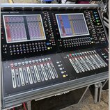 Černý digitální mixovací pult s dvěma velkými barevnými displeji a řadami posuvníků. V levém horním rohu je bílý nápis DiGiCo SD12. Povrch obsahuje m…