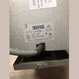 Detail štítku na šedém kovovém zařízení s texturou. Na bílém štítku je logo TRAMAG a nápisy: pri. 220 V, sec. 110 V, L.Nr. D 1601, 50÷60 Hz, 1600 VA,…