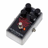 Šedý efekt pedál s povrchem z plstěného materiálu a černým ovládacím panelem. Na panelu je červený nápis Bass Soul Food a bílý nápis electro-harmonix…