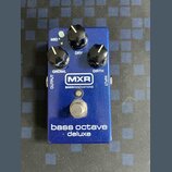 Modrý efekt pedál s nápisy MXR a BASSINNOVATIONS. Na horní části jsou tři černé ovládací knoflíky s popisky MID+, DRY, GROWL a GIRTH. Ve spodní části…