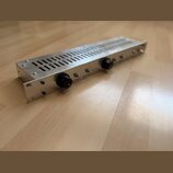 Stříbrné rackové zařízení z kovu s perforovaným horním krytem. Na předním panelu jsou dva černé oválné ovládací knoflíky a nápisy DISTANCE a RELEASE.…