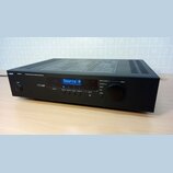 Černý digitální zesilovač s nápisem Apart CONCEPT 1 PROFESSIONAL DIGITAL CONTROLLED AMPLIFIER. Na předním panelu je modrý displej s textem Source A,…