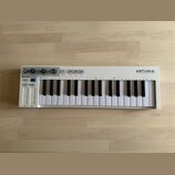 Bílá klaviatura s 32 klávesami. Na pravé straně je nápis ARTURIA a pod ním slogan YOUR EXPERIENCE YOUR SOUND, vlevo je označení KEYSTEP. Horní panel…