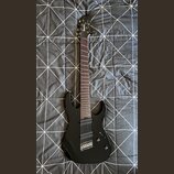 Černá elektrická kytara s tmavým hmatníkem a dvěma humbuckery. Na hlavě je bílý nápis Ibanez. Nástroj vykazuje známky běžného používání, jsou vidět d…