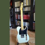 Elektrická kytara typu Telecaster v krémové barvě se světlým hnedem dřevěného krku a hmatníkem. Na hlavě je viditelné logo "Telecaster". Tělo vykazuj…