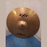 Kruhová mosazná činely s viditelným žebrováním. Na povrchu jsou nápisy ZXT, Rock Crash a 18"/45cm, v dolní části je logo Zildjian. Povrch vykazuje dr…