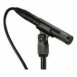 Černý kondenzátorový mikrofon v držáku na stojanu. Na těle mikrofonu je nápis audio-technica a v držáku je viditelné logo značky (písmeno A v kruhu).…