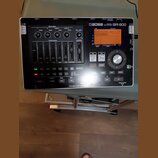 Černý digitální nahrávací zařízení s nápisem BOSS DIGITAL RECORDER BR-800. Přístroj obsahuje displej, několik posuvníků track mixeru, ovládací knoflí…