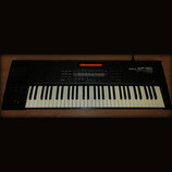 Černý digitální klavír s bílými a černými klávesami. Na pravé straně panelu je bílý nápis Roland XP-50 MUSIC WORKSTATION. V horní části se nachází or…