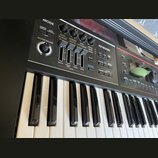 Detailní pohled na ovládací panel a klávesy elektronického klavíru. Na černém panelu jsou umístěny čtyři otočné knoflíky s popisky CUTOFF, RESONANCE,…
