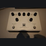 Bílý efekt pedál s nápisem AMPED 1 a podtitulem DEPT. 10 | 100W AMP PEDAL. Uprostřed je logo ve tvaru černé hvězdy v bílém čtverci. Zařízení má šest…