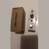 Bílý efekt pedál s nápisy NOISE GATE, Rowin a TRUE BYPASS. Obsahuje jeden ovládací knoflík s popiskem THRESHOLD a přepínač s označením HARD / SOFT. V…