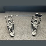 Dvojpedál na buben v černo-stříbrném provedení z kovu. Na obou pedálech je nápis IRON COBRA 200 a logo TAMA. Povrch vykazuje mírné známky používání v…
