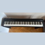 Černá digitální pianola na černém stojanu. Na pravé straně korpusu je bílý nápis Roland a pod ním model FP-30X. Na levé straně jsou umístěna ovládací…