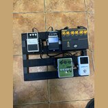 Sada efektových pedálů na černém pedalboardu. Na horní řadě jsou pedály s nápisy Noise Suppressor NS-2, Driver HG-1X a Markbass COMPRESSORE s nápisem…