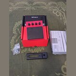 Červený elektronický sampling pad s černou gumovou plochou a nápisem Roland. Na horním ovládacím panelu je uveden model SPD-ONE WAVE PAD a několik ov…