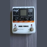 Bílý efekt pedál s nápisem MOD FORCE. Na horní části jsou čtyři černé ovládací knoflíky s popisky SPEED, DEPTH, TWEAK a MIX, displej a nápisy nux, TS…