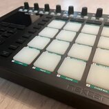 Černý MIDI kontrolér s mřížkou bílých podsvícených padů. Pod pady jsou zelené štítky s nápisy COPY, PASTE, CLEAR a CLEAR ALL. Na přední hraně přístro…