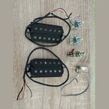 Dva černé humbuckery s černými kryty snímačů a viditelnými polosférickými póly. K oběm snímačům vedou černé kabely s barevnými vodiči. Vedle nich jso…