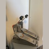 Dvojpedál na buben z kovového materiálu stříbrné barvy s oranžovými detaily. Na obou pedálech je v pravé dolní části nápis Pearl a na šlapkách jsou o…