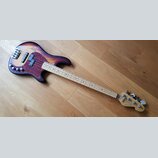 Elektrická basová kytara s tělem v červeno-černém sunburst provedení a tmavě červeným pickguardem. Na hlavě hmatníku je vidět nápis „sandberg“ a logo…