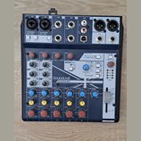 Mixážní pult s modrým povrchem a černým rámem. Na předním panelu je bílý nápis Soundcraft a pod ním model NOTEPAD-8FX. V horní části je sekce EFFECTS…