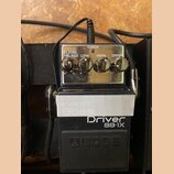 Černý efekt pedál s nápisy Driver BB-1X a logo BOSS. Na horní části jsou čtyři ovládací knoflíky s popisky LEVEL, BLEND, LOW, HIGH a DRIVE a kontrolk…