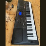 Černý digitální klavír značky YAMAHA s bílými a černými klávesami. Na ovládacím panelu je modře podsvícený displej a nápis YAMAHA. Nástroj je připoje…