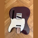 Tělo elektrické kytary v tmavě vínové barvě s bílým pickguardem. Na mostku je viditelný nápis „In-Tune“. V dolní části těla je dřevěný blok s nápisem…