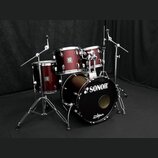 Tmavě červená bicí souprava s chromovaným hardwarem. Na přední straně basového bubnu je bílý nápis SONOR a logo Zildjian. Na ostatních bubnech jsou v…